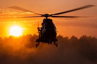 Un hélicoptère de transport Cougar fait exploser la poussière au coucher du soleil