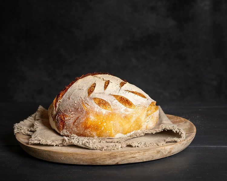 Traditionelles Sauerteigbrot auf einem runden Brett mit Serviette. von John Goossens Photography