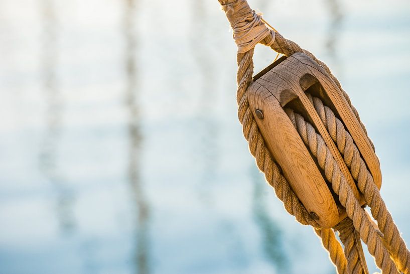 Nautical pulley with ropes of a classic sailing boat and blue sea water background by Alex Winter