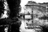 Eenzame krantenbezorger fietst over een brug in IJlst Friesland. One2expose Wout Kok Photography. 