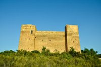 Das Castillo de Forna auf einem großen Felsen, umgeben von grünen Bäumen und Sträuchern unter blauem