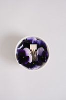 Moderne Parfümflasche in Schale mit Veilchen