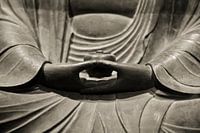 Hands of meditating Buddha statue in sepia