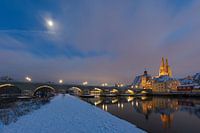Cathedral, stone bridge and old town of Regensburg on the danube river in winter with fresh snow and