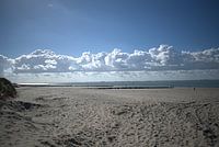 a row of clouds above the beach and the sea