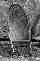 Kapotte rieten stoel bij een verlaten huis