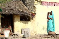 Femme avec bébé en face de leur maison
