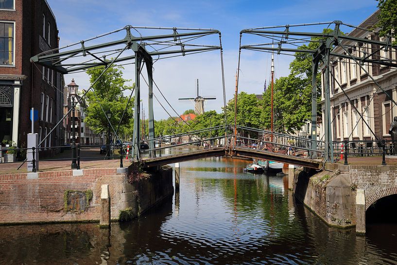 Historical drawbridge across a canal and a windmill in Schiedam, Holland by Jan Kranendonk
