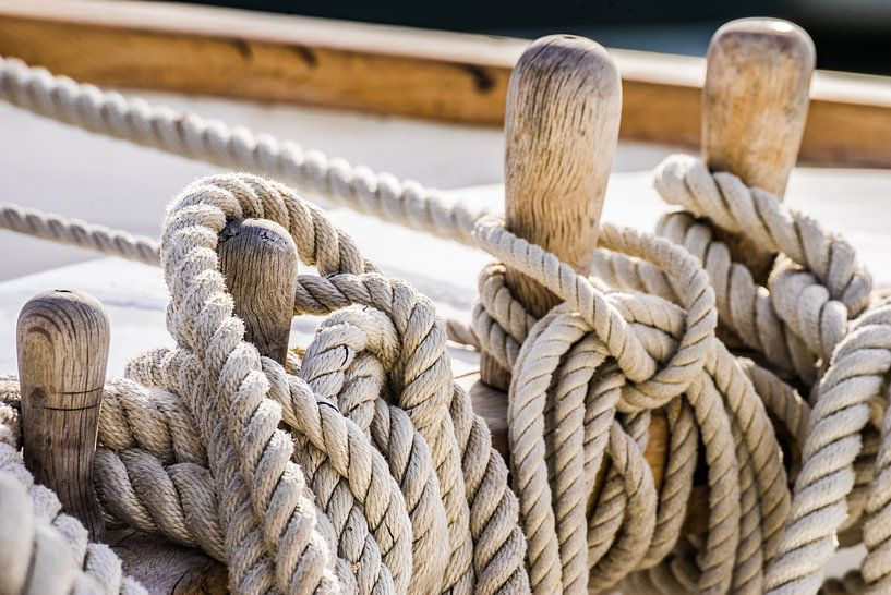 Close-up of moored ropes on wooden cleats on old sailing boat by Alex Winter