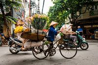 Frau mit einem Fahrrad voll von Blumen in Hanoi Vietnam