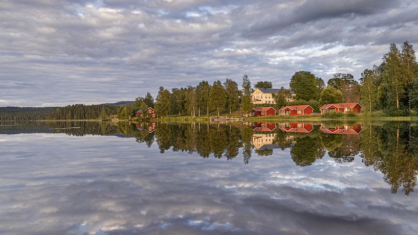 Typique de la Suède - Les maisons en bois rouge et les arbres se reflètent dans l'eau par Bram Lubbers