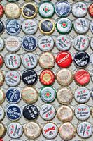 Diverses capsules de bouteilles de bière de recouvrement collé sur un mur