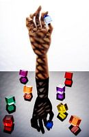 Wooden hand holding a blue cube between thumb and forefinger, surrounded by 8 multicoloured cubes.