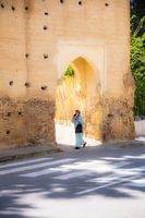 Arab woman walks in front of ancient city wall