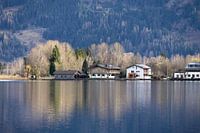 Spiegelungen von Häusern am Rande eines Bergsees.