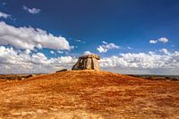 Prehistoric Dolmen  under a vibrant blue sky with clouds. Megalithic tomb in Alentejo, Portugal.