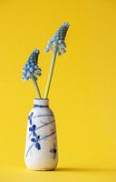 Kleine chinesische antike Vase mit zwei blauen Weintrauben auf gelbem Hintergrund.