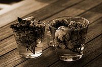 Beautiful fresh mixed flowers arranged in glass vases on a wooden table surface in sepia.