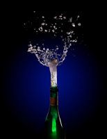 Champagnefles explosie met kurk knallende plons tegen een donkere achtergrond met blauw tot zwart ve