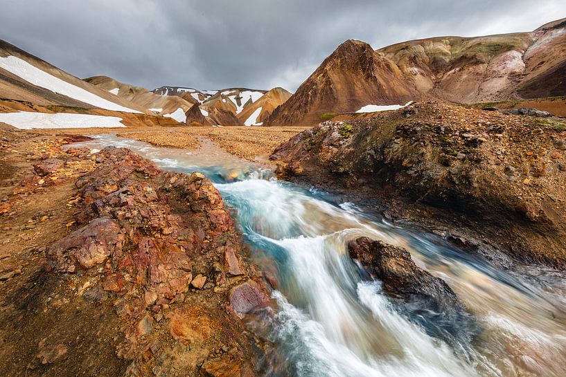 Flowing stream surrounded by mountains by Martijn Smeets