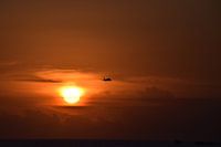 Vliegtuig tijdens een dieprode zonsondergang