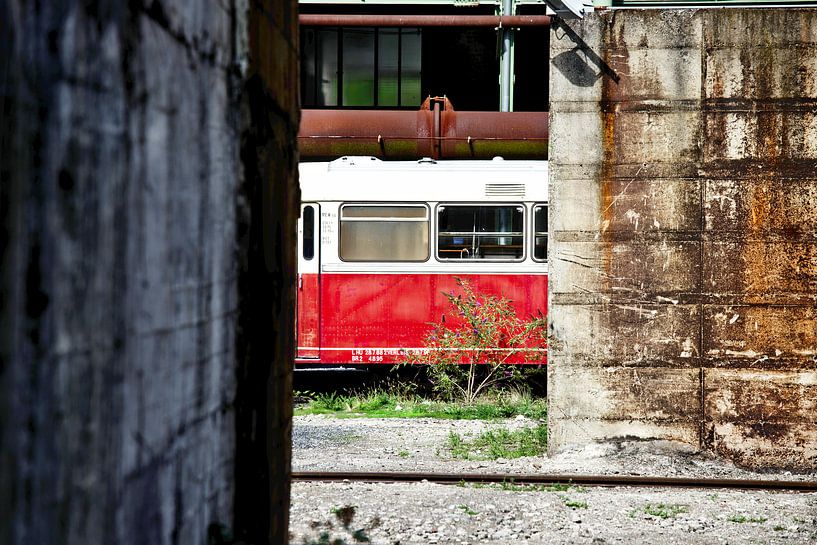 Old deserted train between buildings by Jan Brons