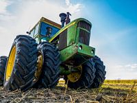 Green John Deere tractor on a cultivated field