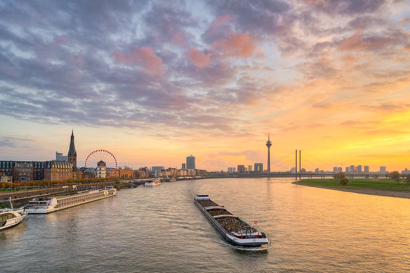Die Düsseldorfer Skyline mit Schiff auf dem Rhein bei Sonnenuntergang von Michael Valjak