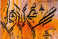 Calligraphie arabe sur un mur jaune.