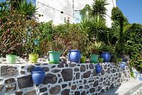 Griechische Mauer mit bunten Blumenkübeln