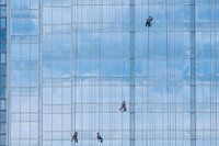 4 window cleaners on blue glass facade