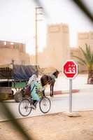 Arab woman cycles through Moroccan street scene