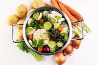 Brühe mit Karotten, Zwiebeln, verschiedenem frischem Gemüse in einem Topf - bunte frische klare Früh