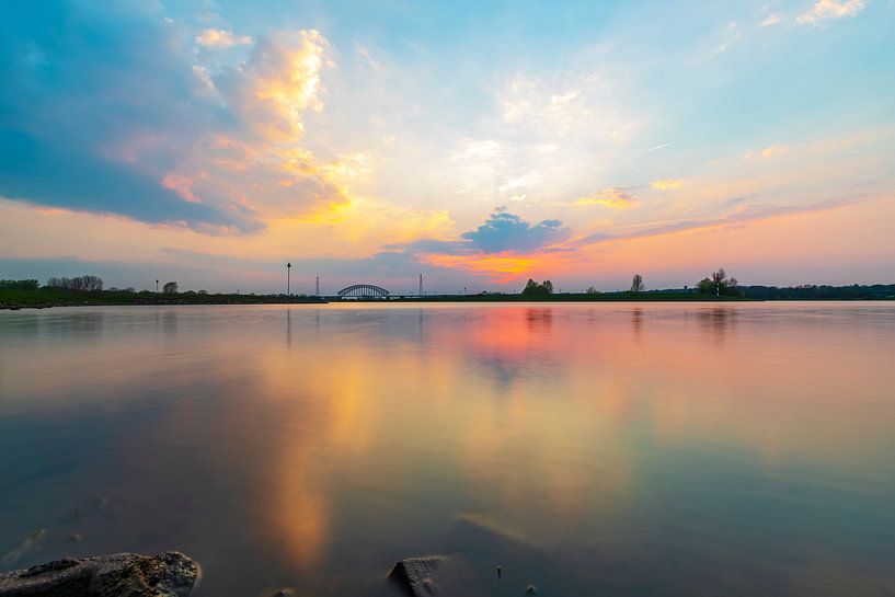 Buntes Abendlicht, das sich im Wasser spiegelt und nach Sonnenuntergang leuchtet. von Arjan Almekinders