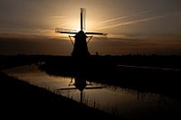 Hempenser poldermolen spiegel in de vaart bij zonsopkomst.