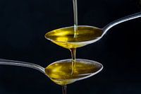fließendes Olivenöl in kleine Löffel