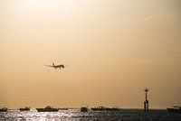 Landend vliegtuig boven zee tijdens zonsondergang