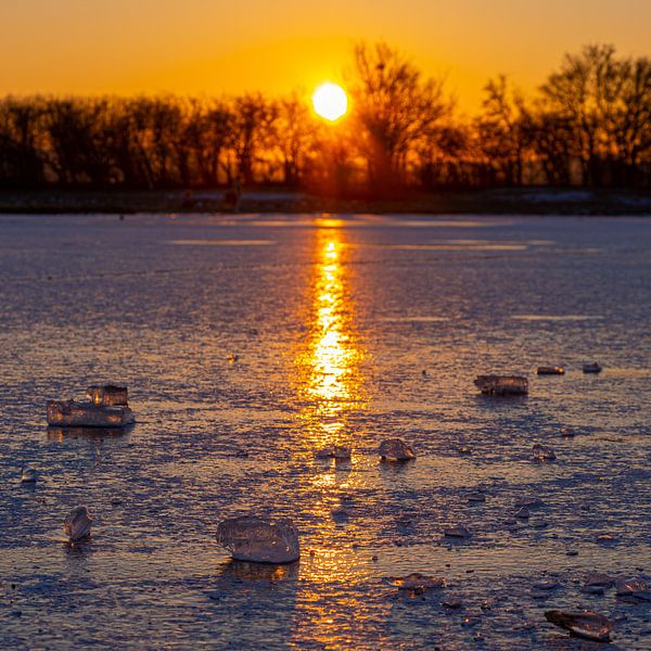 Chunk of ice on a frozen lake during a warm sunrise by Kim Willems