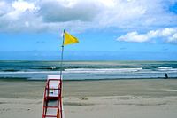 Drapeau de plage jaune jusqu'à la chaise de sauveteur