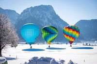 Hot air balloons adorn the sky over a snowy Inzell in Germany