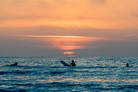 Surfers admire the sunset in the water at Terschelling
