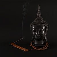 Buddha with incense against a black background