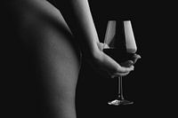 La photo d'une femme nue tenant un verre de vin derrière son dos.