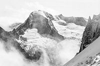 Robuste vergletscherte Bergspitze ragt schwarz-weiß über die Wolken hinaus.