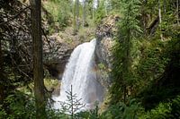 Rainbow in front of a rough waterfall in the forest