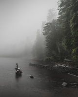 Landschapsfoto van een mistig meer met een standbeeld van een zeemeerm