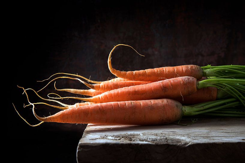 Carottes avec des feuilles vertes sur une table en bois rustique sur un fond sombre avec espace de c par Maren Winter
