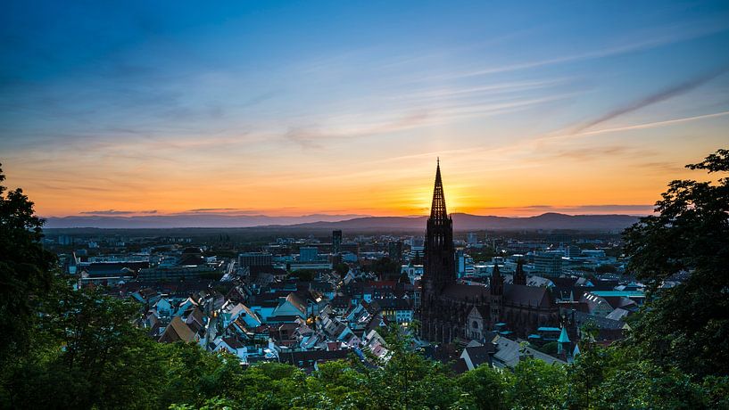 Freiburg im Breisgau orange sunset behind steeple of minster cathedral by adventure-photos