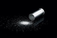 Salzstreuer auf schwarzem Hintergrund mit Salzkörnern.