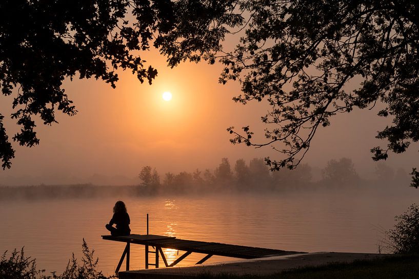 silhouette girl at wooden jetty during sunset in the early morning over the river maas in limburg in by ChrisWillemsen